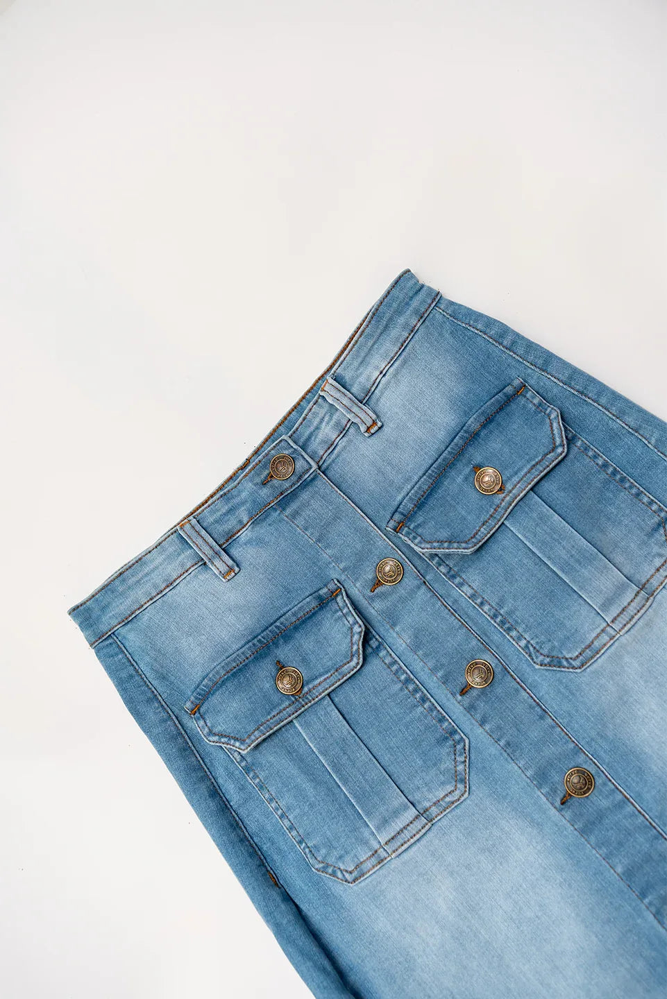 Button and waist detail of light wash denim skirt