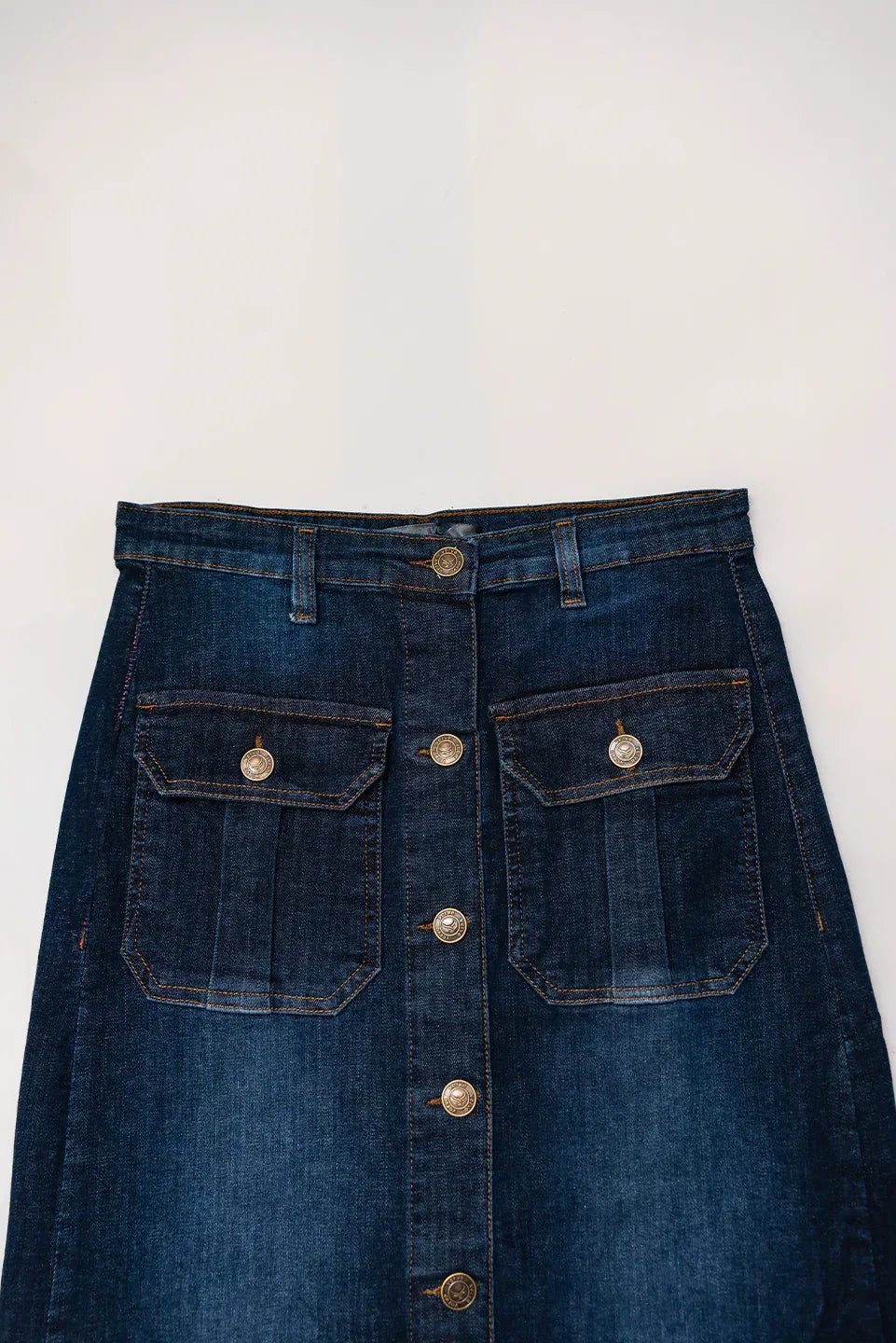 High-waist detail of blue denim button-down skirt, belt loops, front pockets, stitched design